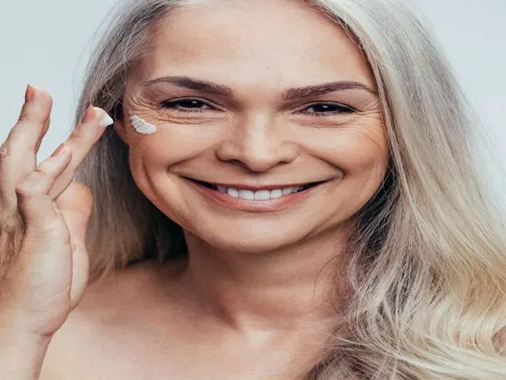Smiling mid adult caucasian woman applying anti aging cream on her face