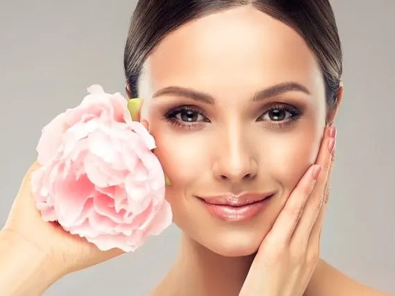 Beautiful young woman with delicate peony flower.